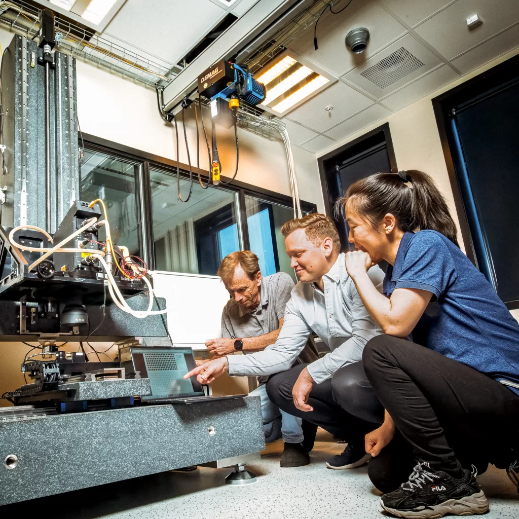 Three Visitech colleagues at a test stage, looking at a laptop
